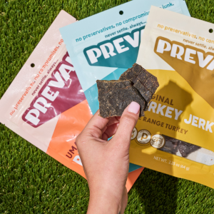 Customer holds 3 varieties of Prevail Jerky gluten-free jerky snack in her hand