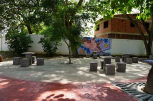 An outside paved area, in grey and red, with cool stone seats, shaded by beautiful green trees in Colombia