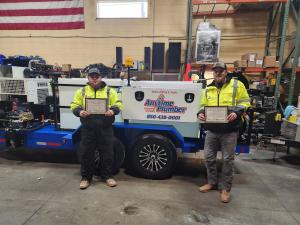 Two Anytime Plumber technicians standing with their hydro jetting course certificates.