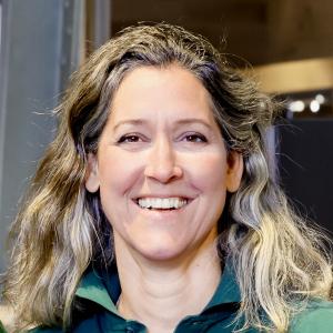 A head and shoulders photo of OneThird CEO Henrike Langbroek. She is smiling and has shoulder length dark blonde hair and is wearing a dark green polo shirt.