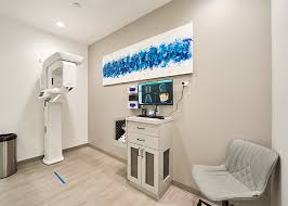 A modern dental imaging room at Love Dental, featuring a dental x-ray machine, a computer workstation, and sleek decor for a comfortable patient experience.