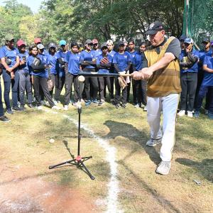 Young Baseball players at Diamond Dreams Academy, engaged in focused training drills on the field, with a DDA coach demonstrating a batting move in a open field