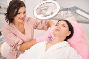 A female esthetician administers beauty injections to a client's neck area.