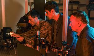 Naval Postgraduate School (NPS) faculty researchers Brij Agrawal (right) and Leonardo Herrera observe U.S. Navy Ensign Nicholas Messina positioning a Reaper drone model in an optical beam path to simulate a distant flying drone.