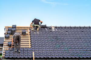 Craftsmen perform storm damage restoration services, building a new roof from ceramic tiles to ensure durability and weather resistance.