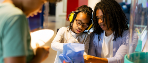 A child with headphones and an adult engage in a fun activity together, surrounded by colorful decor and materials.