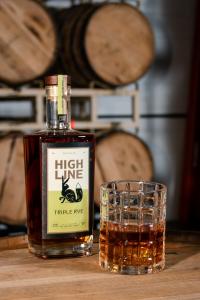 Highline Triple Rye on the head of a whiskey barrel with a dram in a crystal glass