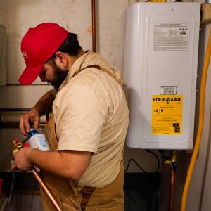 J. Blanton Plumbing technician conducting water heater maintenance, highlighting the company’s expertise in plumbing repairs, frozen pipe repair, and water heater maintenance while supporting the District 113 Foundation Pizza Bowl and Baker's Showcase.