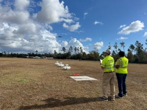 An Instructor directs a remote pilot student as she flies a quadcopter drone over a NIST bucket training lane