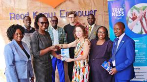 Trueness Project's President and Executive Director, M. Teresa Lawrence (front right) hands over "Leading Forward: Kereri Girls' Leadership Journey" book to Philomena Mwirigi, Director - Acquisition and Distribution Directorate, KNLS. Photo: Godfrey Atsing'a.