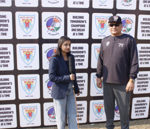 A woman from the media holding a microphone stands next to Mr. Kanwal Sra, CEO of DDA. He is wearing sunglasses and a cap with DDA on it. They are in front of a banner with DDA logo and text saying, Building Tomorrows Champions, One Dream at a Time.