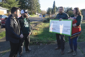 Marine veteran Chris Weise and his family receive a $29,860 donation from DaBella and Heroes Homestead for a new roof, standing outside their home in Gresham, Oregon.