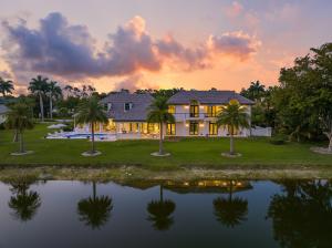 Dusk shot of the rear of 6536 Highcroft Drive, showcasing the outdoor living space, pool, and serene water views