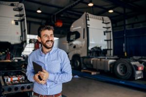 Truck repair shop owner standing proudly in front of his business, ready to serve customers.