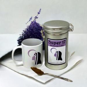 a tin of coffee with a mug and spoon and a flower bouquet of lavender behind