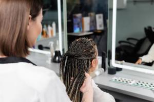 A hairstylist intricately braids a female client’s hair in a salon.