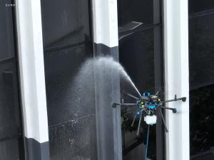 A drone spraying water on the exterior windows of a high-rise building, demonstrating SprayTech’s FAA-certified drone-powered cleaning technology at California Bank & Trust, Del Amo, Torrance, CA.