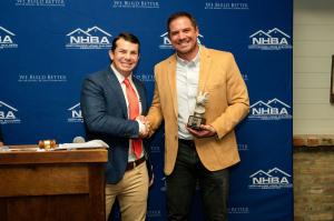 Photo of two individuals shaking hands and award being handed over.