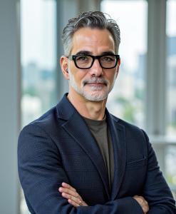 Dr Seth Dobrin CEO Qantm AI inside office wearing a glasses and blue jacket arms crossed