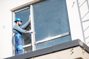 A technician performing an emergency glass repair service professionally mounting a new window to replace damaged glass in a commercial building.