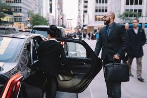 A well-dressed couple boarding a sleek black vehicle, enjoying the comfort and convenience of private car services for their upscale travel needs.