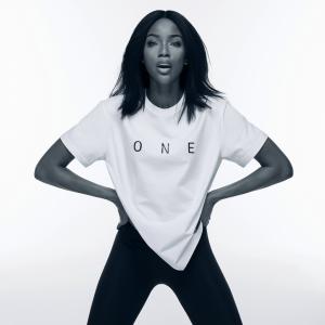 Female Model In Black & White Photo Stands Hands On Hip In Authentic Confidence in Self Wearing A White One T-Shirt With The Word "ONE" Across The Chest of The Confident Model.