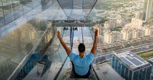 A man sliding at the glass floors on the Sky Views Observatory