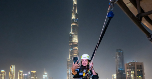 A girl at the Sky Views Observatory swing taking a picture with Burj Khalifa behind her at night