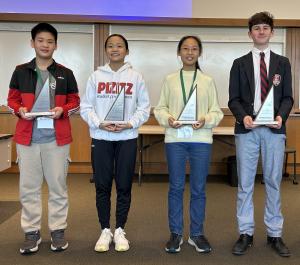 Four middle school students hold trophies.