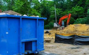 A blue commercial dumpster on a construction site.