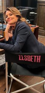 Actress Alison Chace sits in a chair working behind the scenes of the television show Elsbeth