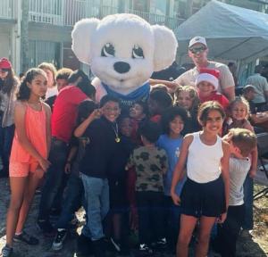 Christmas cheer in every hug: Kids sharing joyful moments with the mascot at the holiday giveaway