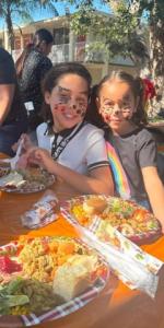 Smiles and Festive Fun: Kids enjoying a meal and celebrating with painted faces at the Christmas giveaway