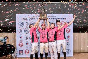 a team of arena polo players lifts a large bronze trophy over their heads in celebration of winning the U.S. Open Arena Polo Championship