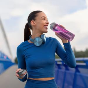 A woman pauses during her workout to hydrate with the new Thermos Brand Icon™ Lightweight Water Bottle in Aubergine.