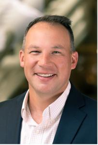 Steven Baer, newly appointed Field CISO at Digital Asset Redemption (DAR), smiling in a professional headshot. He is wearing a navy blazer with a light pink checkered shirt against a softly blurred background.