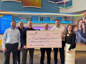 Six people stand in a hospital setting with an oversized check, marking Silverman Law’s $5,000 donation to Shodair Children’s Hospital for their giving partnership.