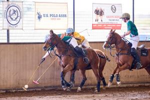 two arena polo players, one man, one woman in a play along the wall