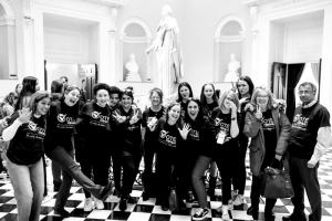 In this black and white photo, a group of advocates, including kids and adults, celebrates with fun expressions in the rotunda of the Virginia state capitol.