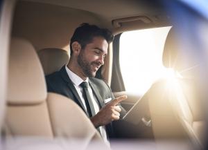 Smiling business executive in formal attire comfortably seated in a luxury vehicle during a chauffeur service provided by Mega Transfers