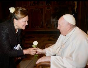 A woman gives a white rose to Pope Francis