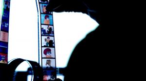 Uncommon Ephemera founder Mark O'Brien holds up a Scooby-Doo filmstrip about acne in front of a lightbox, showing the colorful frames that make up the filmstrip.