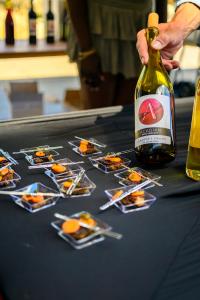 A hand offers a bottle of Acadian Wine Company Cabernet Franc next to an array of small plates with fancy food.