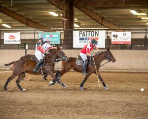 a woman on a polo horse chases after another player during an arena polo match