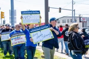 Workers holding signs protesting offshoring and other issues at General Electric Aviation