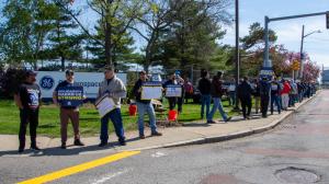 Workers holding signs protesting offshoring and other issues at General Electric Aviation