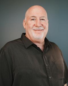 Photo of Jeff Schmidt. CFO of PayCompass, smiling wearing a black collared shirt