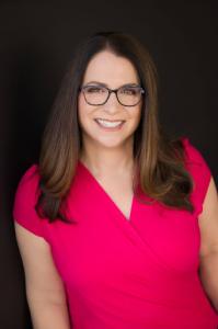 Image of Julie Williamson PhD, author of Make HOW Matter in red shirt, wearing brown glasses and smiling