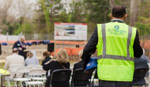 Ribbon cutting cerimony with man standing in a Syncon LLC uniform