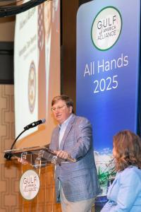 Mississippi Governor Tate Reeves, standing on stage, welcomes attendees to Alliance All Hands Meeting.